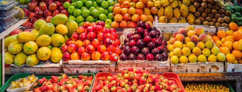A photo of an abundance of different fruits sit in plastic crates at a market stall.